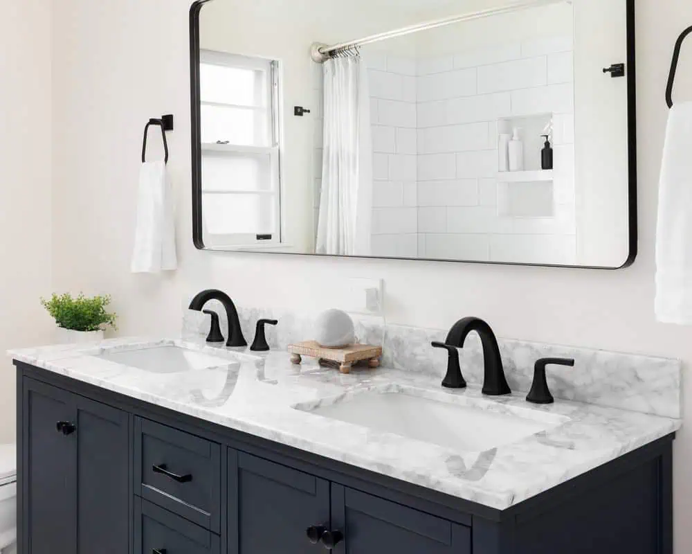Modern bathroom with a double sink vanity featuring a white marble countertop and black faucets.
