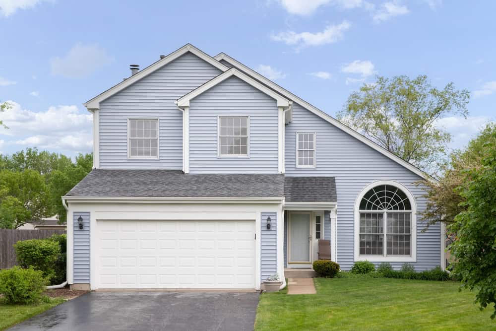 A charming two-story house in Dutchess County, NY, boasts light blue siding with white trim and a large arched window.