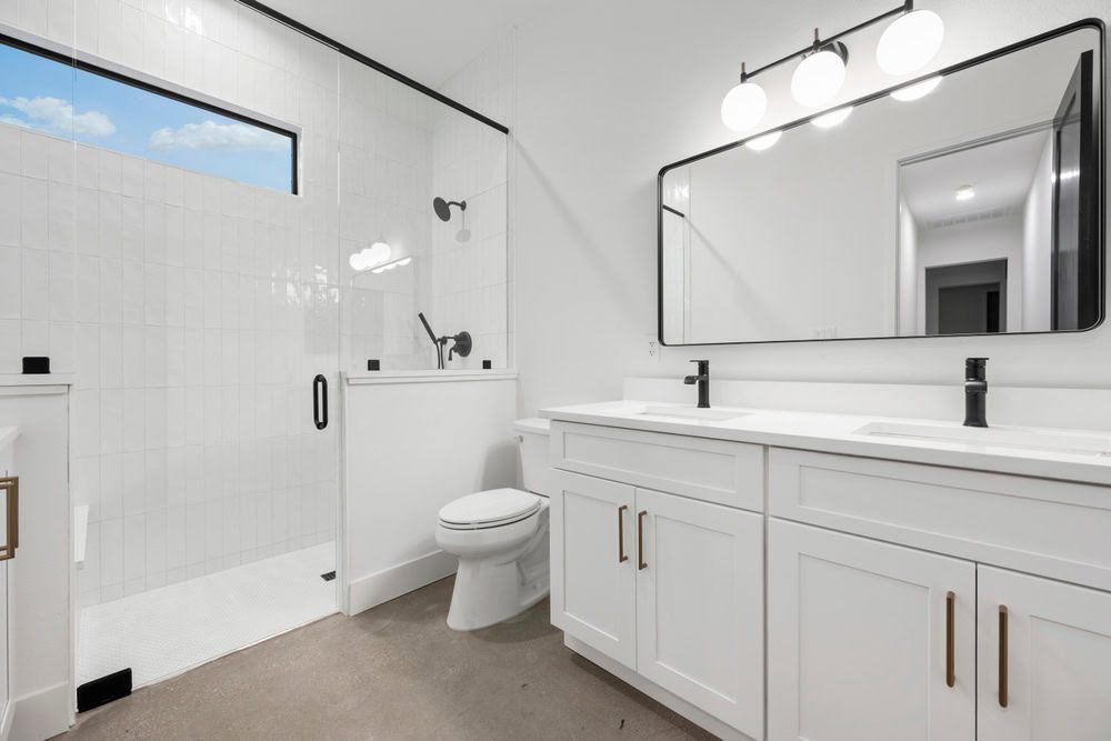 A modern bathroom with white cabinetry, double sinks, and black faucets.