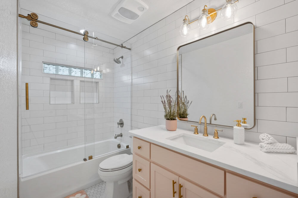 Modern bathroom with white subway tile walls, a glass-enclosed bathtub, and a vanity with a marble countertop.
