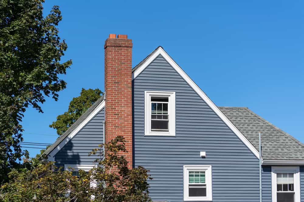 A house featuring blue siding, expertly installed by a general contractor from Orange County, NY, showcases a gabled roof with gray shingles.