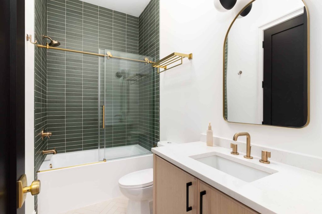 A modern bathroom showcases the skill of Home Remodeling Orange County NY, with a vanity featuring a rectangular sink and brass fixtures.