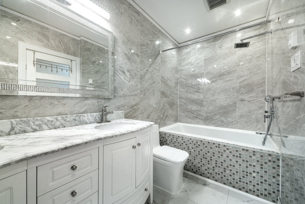 Elegant bathroom with gray marble walls, white cabinetry, and a marble countertop.