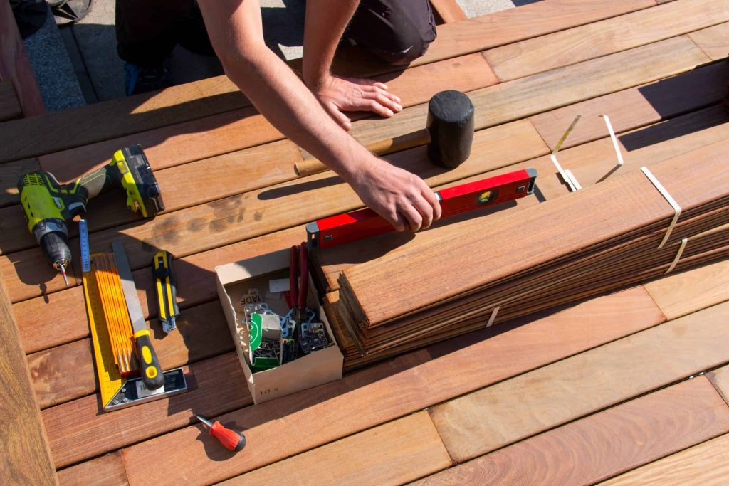 A person assembling a wooden deck, possibly part of a home remodeling project in Orange County NY.