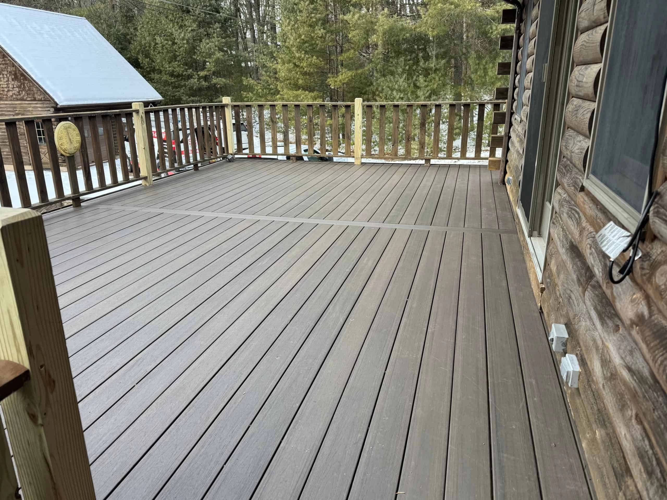 A wooden deck with railings, attached to a log cabin.